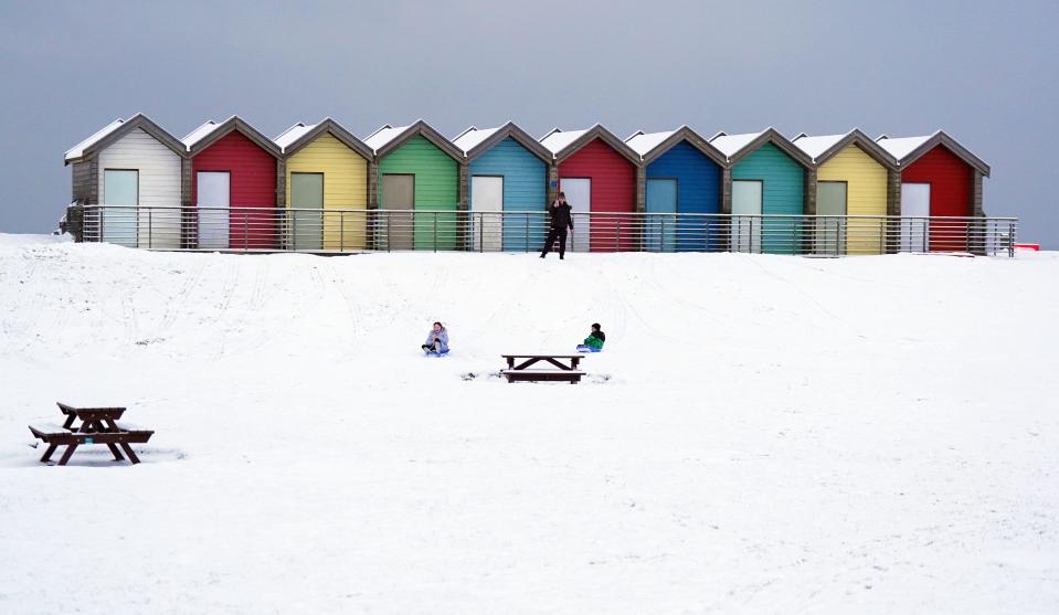 People ride sledges besides the beach huts at Blyth in Northumberland (Owen Humphreys/PA Wire)