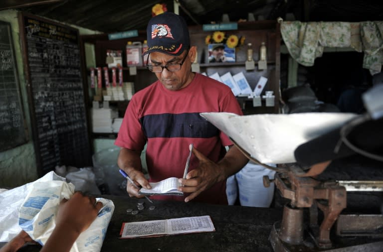 A grocer writes on a ration book in San Luis, Cuba -- an illustration of how each Cuban household receives certain basic foods every month for a fraction of their market value