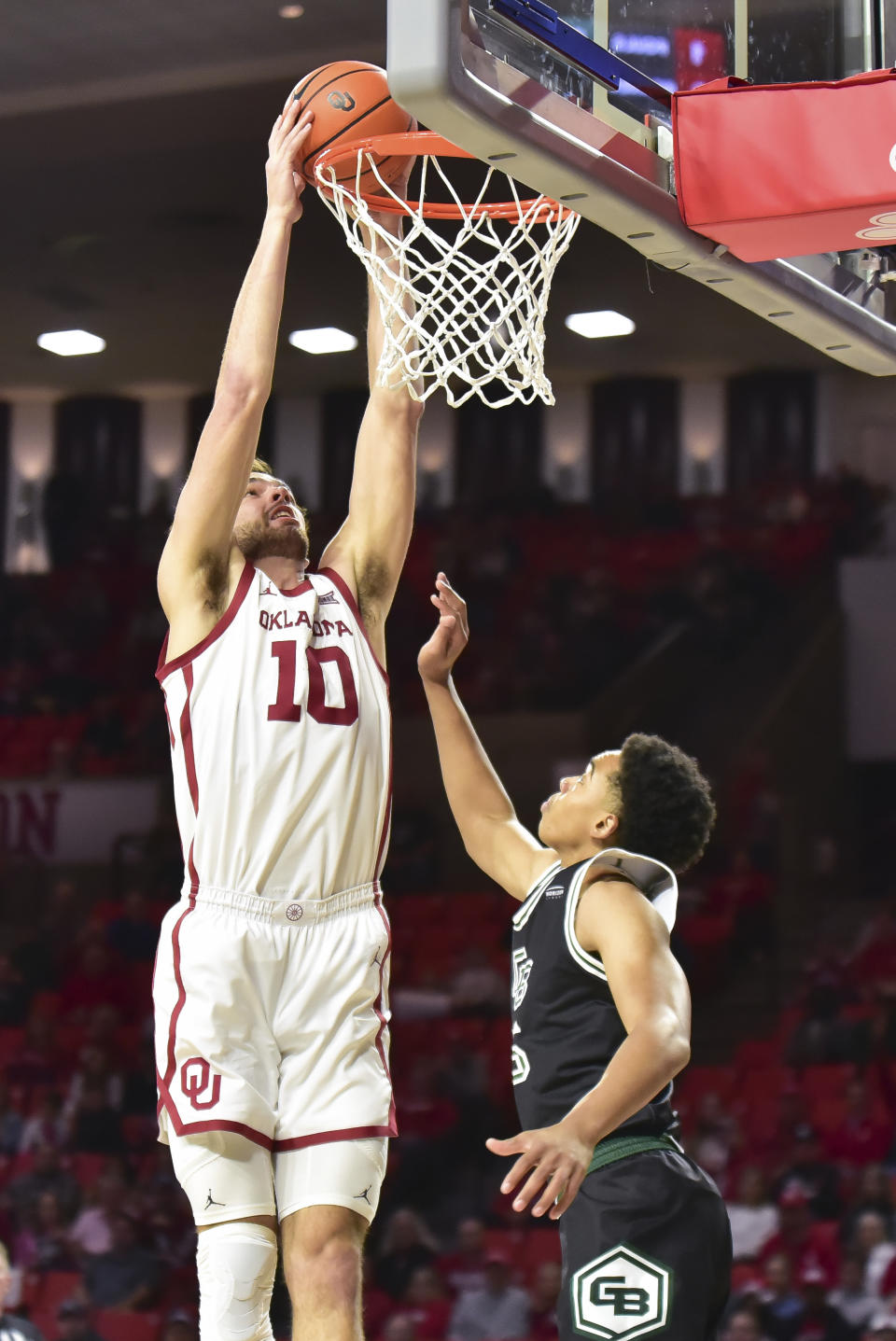 Oklahoma forward Sam Godwin dunks over Green Bay guard David Douglas Jr. during the first half of an NCAA college basketball game Saturday, Dec. 16, 2023, in Norman, Okla. (AP Photo/Kyle Phillips)