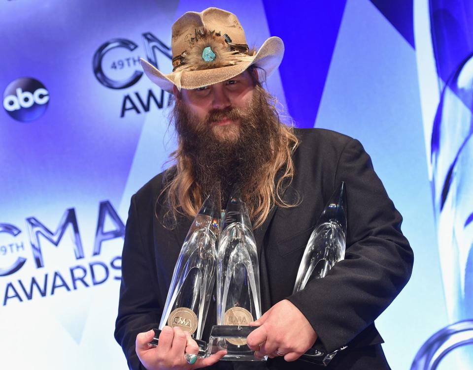 chris stapleton holding three crystal trophies from an award show