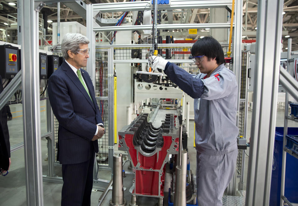 U.S. Secretary of State John Kerry, left, looks on as an engine is built during a tour of the Foton Cummins Engine plant in Beijing, China Saturday, Feb. 15, 2014. Kerry toured the plant and made remarks on climate change cooperation between the United States and China. (AP Photo/Evan Vucci, Pool)