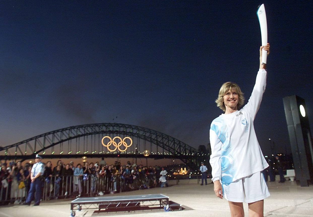 Olivia Newton-John holds the Olympic torch before the Sydney Harbour Bridge, one day before the start of the Sydney 2000 Olympic Games. 