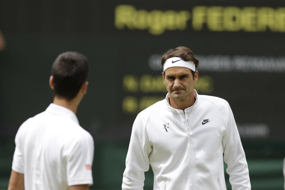 Roger Federer of Switzerland and Novak Djokovic of Serbia, left, meet at the net ahead of the men's singles final at the All England Lawn Tennis Championships in Wimbledon, London, Sunday July 12, 2015. (AP Photo/Pavel Golovkin)