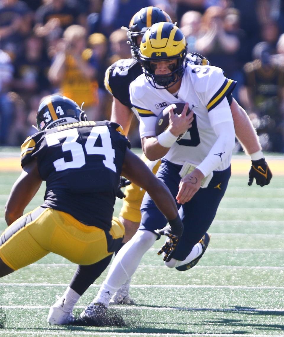 Michigan quarterback J.J. McCarthy scrambles on a keeper in front of Iowa linebacker Jay Higgins during the first half on Saturday, Oct. 1, 2022, in Iowa City, Iowa.