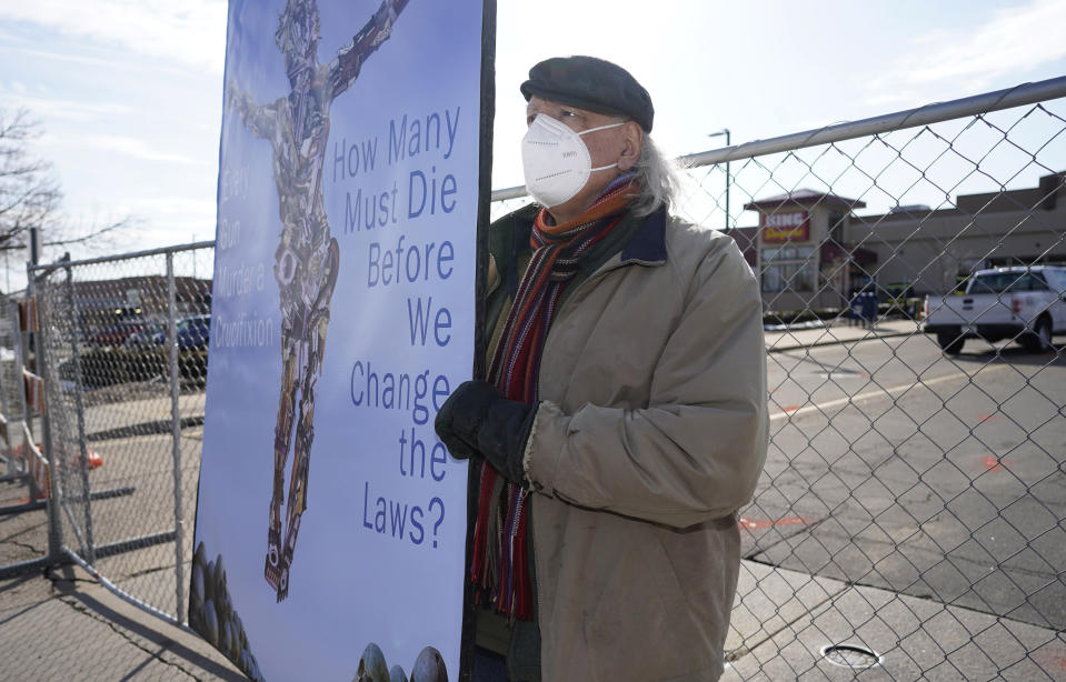 Stephen Parlota of Boulder, Colo., holds his handmade sign in front of a makeshift fence put up around the parking lot outside a King Soopers grocery store where a mass shooting took place Tuesday, March 23, 2021, in Boulder, Colo. (AP Photo/David Zalubowski)