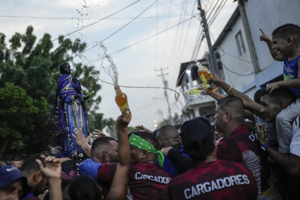 Devotees bathe a statue of San Benito de Palermo with rum during a procession honoring their patron saint, in Cabimas, Venezuela, Dec. 27, 2023. (AP Photo/Matias Delacroix)