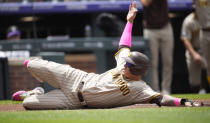 San Diego Padres' Manny Machado slides safely across home plate to score on a single hit by Gary Sanchez during the first inning of a baseball game against the Colorado Rockies, Saturday, June 10, 2023, in Denver. (AP Photo/David Zalubowski)