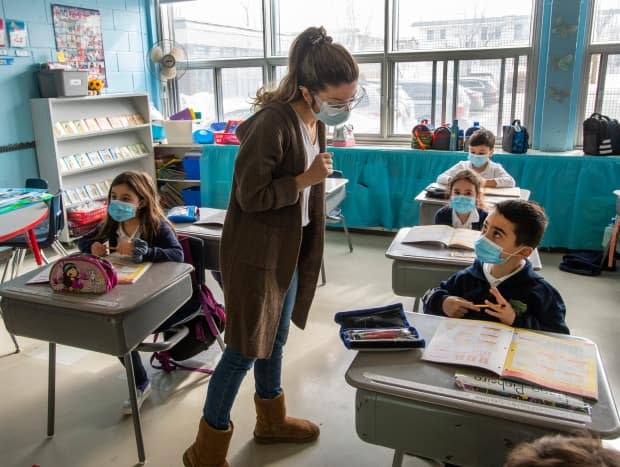 A Montreal teacher and her grade one students wear masks as they attend class. The Calgary Board of Education said Tuesday it will require mandatory vaccination against COVID-19 for employees, volunteers and partners by Dec. 17. (Ryan Remiorz/The Canadian Press - image credit)