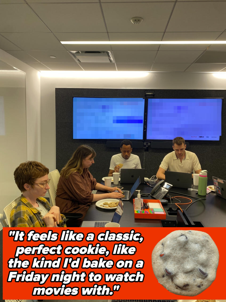 A group of four people at a conference table with laptops and plates of cookies, working together in a modern office setting