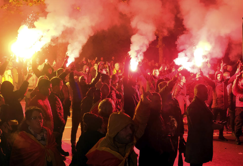 Protesters light torches during a rally in front of the parliament building in Podgorica, Montenegro, Monday, Dec. 12, 2022. Clashes erupted on Monday during an opposition protest in Montenegro reflecting a deep political crisis between the pro-Western and pro-Serb and pro-Russian camps in the small Balkan country that is a member of NATO. (AP Photo/Risto Bozovic)