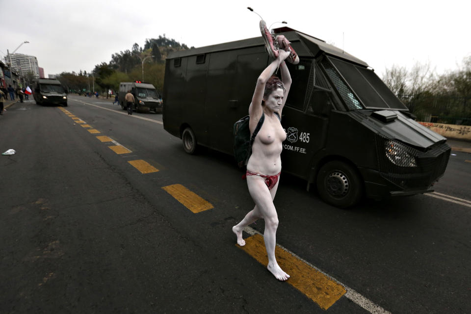 A half-naked demonstrator runs alongside a riot police vehicle as Human Rights activists march in Santiago, on Sep. 11, 2016 commemorating the 43rd anniversary of the military coup led by General Augusto Pinochet that deposed President Salvador Allende.