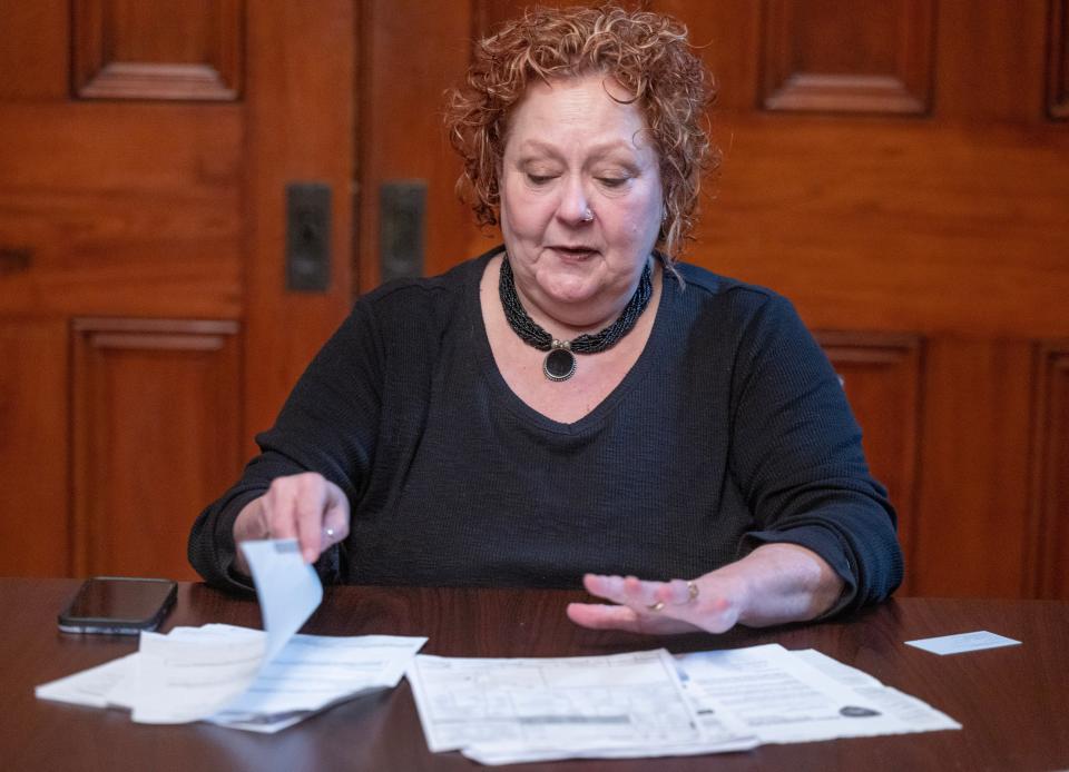 Tami Huff flips through bills resulting from her Feb. 10 collision with a Perry Township police cruiser that was going to join other law enforcement in pursuing a fleeing motorist. Photo taken March, 26, 2024.