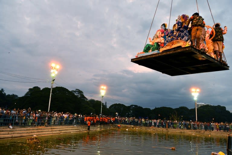 <p>Volunteers are lowered on a platform with large idols of Hindu elephant-headed god Ganesh brought by Hindu devotees for immersion at a water tank during the Ganesh Chaturthi festival in Bangalore on September 7, 2016. </p>