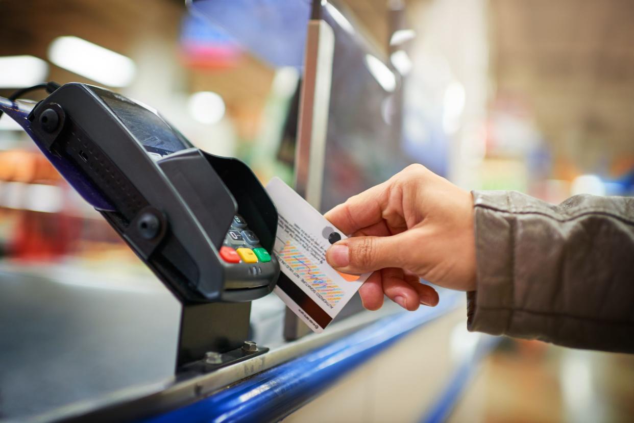 A customer swiping their card in a pin pad at a store.