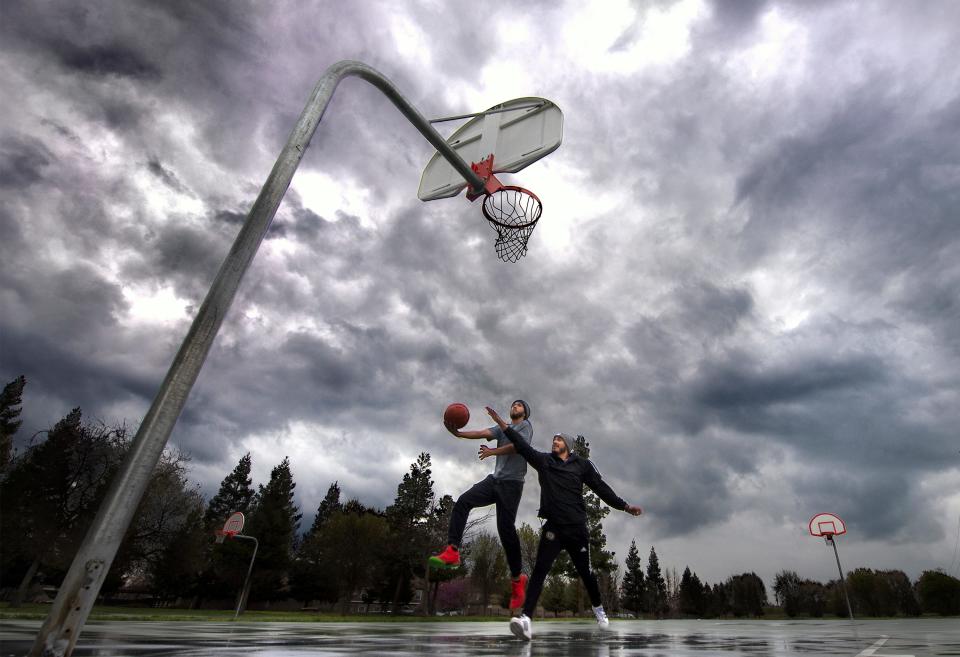 Angel Velasco, left, and Ryan Hanson don't let a few sprinkles stop them from playing a little one-on-one on the rain-slickened basketball courts at Faklis Park in Stockton.