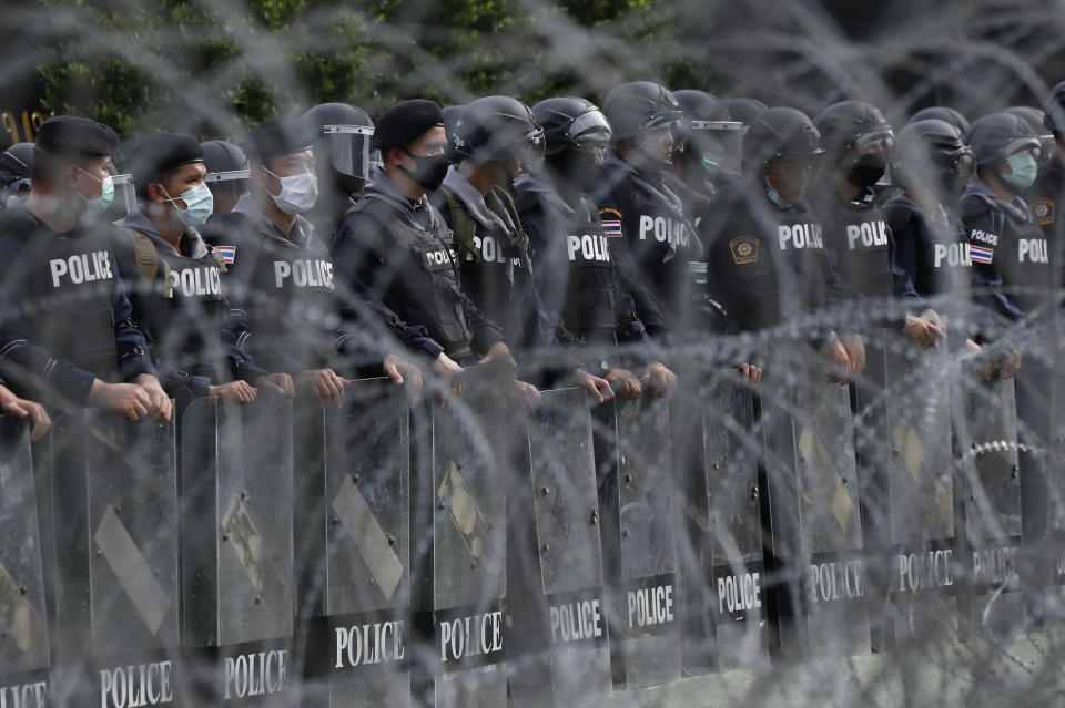 Police stand guard behind barbed wire barricading the base entrance of the 11th Infantry Regiment, a palace security unit under direct command of the Thai king, as they await for the arrival of protesters Sunday, Nov. 29, 2020 in Bangkok, Thailand. Pro-democracy demonstrators are continuing their protests calling for the government to step down and reforms to the constitution and the monarchy, despite legal charges being filed against them and the possibility of violence from their opponents or a military crackdown. (AP Photo/Sakchai Lalit)