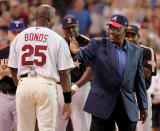 FILE- In this July 12, 2004, file photo, home run record holder Hank Aaron greets San Francisco Giants slugger Barry Bonds before the start of the All-Star Home Run Derby in Houston. Hank Aaron, who endured racist threats with stoic dignity during his pursuit of Babe Ruth’s home run record and gracefully left his mark as one of baseball’s greatest all-around players, died Friday. He was 86. The Atlanta Braves, Aaron's longtime team, said he died peacefully in his sleep. No cause was given.(AP Photo/Eric Gay, File)