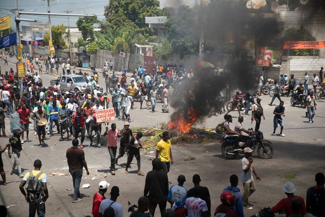 People walk around burning tires set up by protesters during a protest to demand that Haitian Prime Minister Ariel Henry step down and a call for a better quality of life, in Port-au-Prince, Haiti, Wednesday, Sept. 7, 2022.