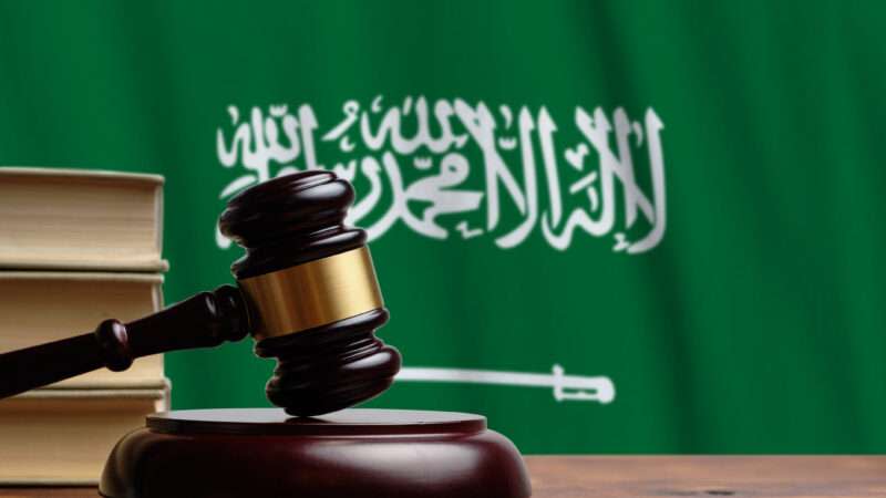 A judge's gavel against the backdrop of the flag of Saudi Arabia.