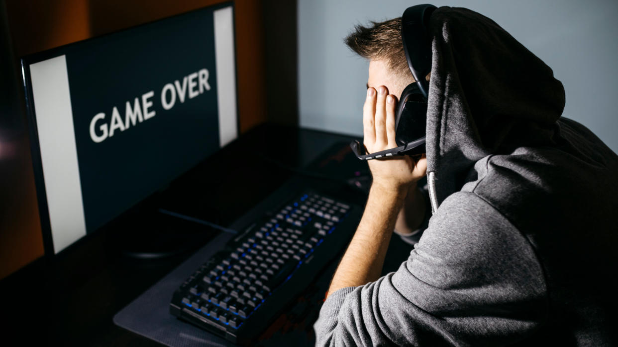  Gamer with head in hands looking at game over screen 