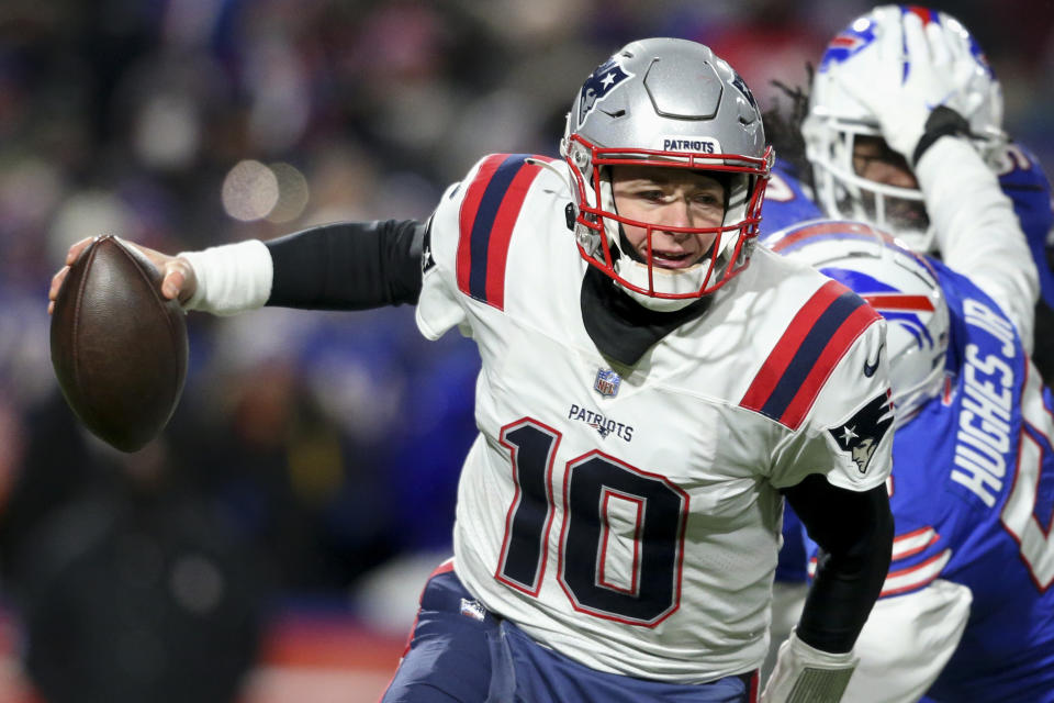 New England Patriots quarterback Mac Jones (10) runs the ball under pressure from Buffalo Bills defensive end Jerry Hughes (55) during the first half of an NFL wild-card playoff football game, Saturday, Jan. 15, 2022, in Orchard Park, N.Y. (AP Photo/Joshua Bessex)