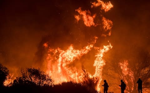 Motorists on Highway 101 watch flames from the Thomas fire leap above the roadway north of Ventura - Credit: AP