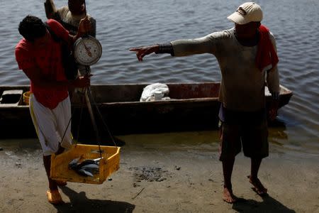 A man weighs fish that he intends to barter for basic staples in Rio Chico, Venezuela June 14, 2018. Picture taken June 14, 2018. REUTERS/Marco Bello