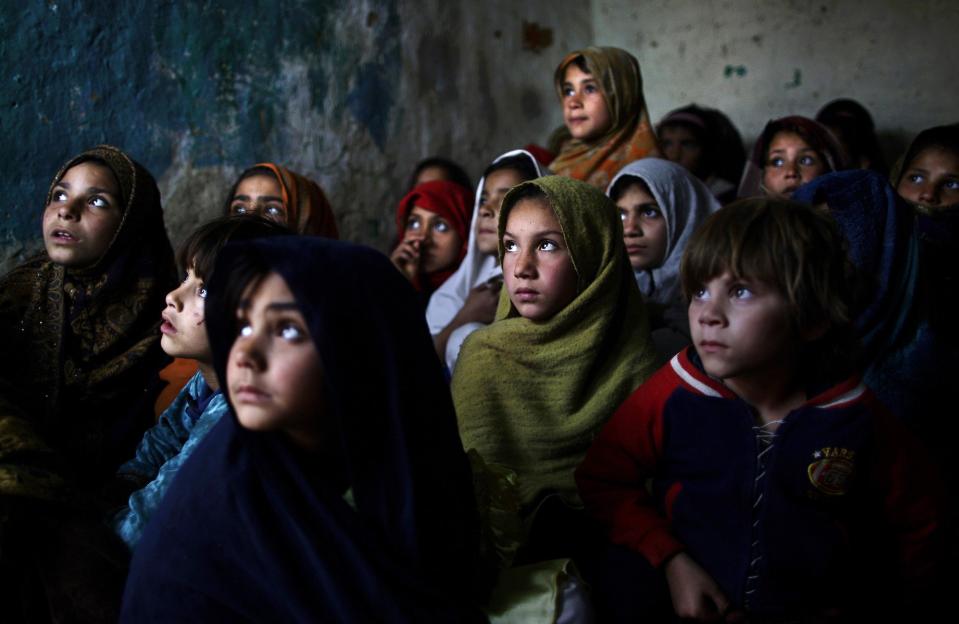 In this Thursday, Jan. 31, 2013, photo, Pakistani schoolgirls, who were displaced with their families from Pakistan's tribal areas due to fighting between militants and the army, listen to their teacher, not seen, while a health worker visiting their school to give polio vaccines, in a poor neighborhood on the outskirts of Islamabad, Pakistan. Wonder Woman and Supergirl now have a Pakistani counterpart in the pantheon of female superheroes _ one who shows a lot less skin. Meet Burka Avenger: a mild-mannered teacher with secret martial arts skills who uses a flowing black burka to hide her identity as she fights local thugs seeking to shut down the girls' school where she works. Sadly, it's a battle Pakistanis are all too familiar with in the real world.(AP Photo/Muhammed Muheisen)