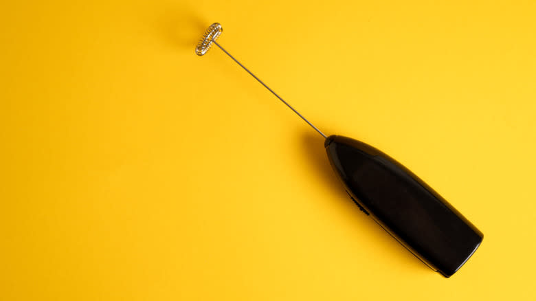 A milk frother on a yellow background