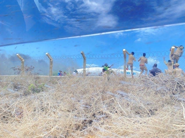 Somalia Danab brigade commandos climb a fence to get to a Jubba Airlines aircraft that crash-landed July 18, 2022, at Mogadishu International Airport, Mogadishu, Somalia. Three 2nd Security Force Assistance Brigade soldiers from Fort Bragg helped first responders care for 16 injured passengers.