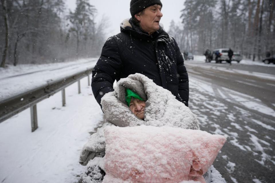 An elderly woman is coated in snow as she sits in a wheelchair after being evacuated from Irpin, on the outskirts of Kyiv, Ukraine (AP)