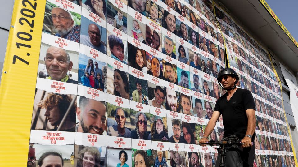 A man passes by a building covered with photos of hostages who have been released or are still being held in the Gaza Strip, on March 26, 2024 in Tel Aviv, Israel. - Amir Levy/Getty Images