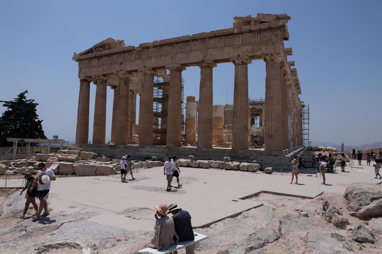 Visitors walk near the Parthenon temple, which sits atop Acropolis hill, during a heatwave in Athens (REUTERS)