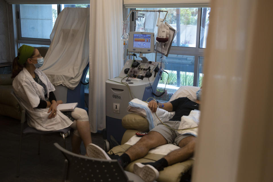 In this May 19, 2020 photo, an Israeli man donates bone marrow for transplant at the Israeli Ezer Mizion bone marrow registry, in the Israeli central city of Petah Tikvah. Over the past two months, as air travel has ground to a halt, Mishel Zrian has criss-crossed the Atlantic and the United States dozens of times, sleeping in empty airports and unable to return home to see his family in Israel, all in a race against time to deliver life-saving transplants. (AP Photo/Sebastian Scheiner)