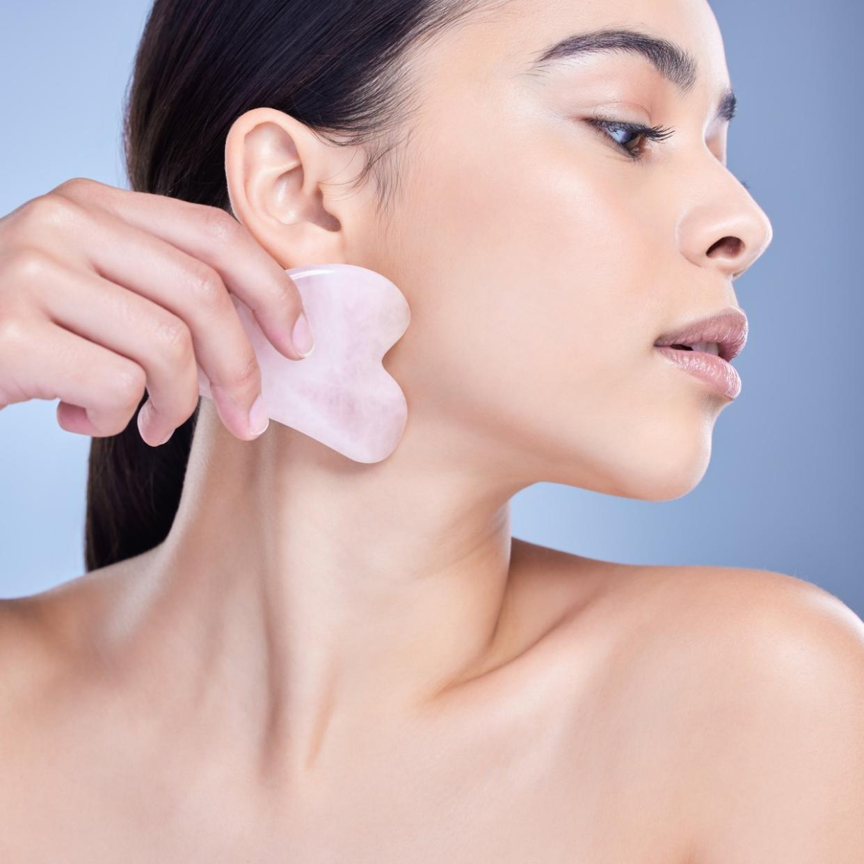  Woman using a rose quartz gua sha. 