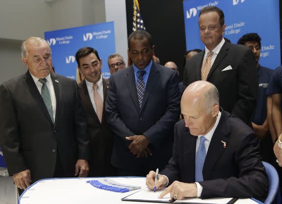 Florida Gov. Rick Scott, right, on June 28 signed legislation that requires school boards to hire an "unbiased hearing officer" who will handle complaints about instructional materials used in local schools.