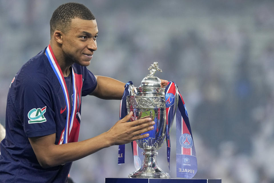 PSG's Kylian Mbappe puts his hand on the trophy during the presentation ceremony after the French Cup final soccer match between Lyon and PSG at the Pierre Mauroy stadium in Villeneuve d'Ascq, northern France, Saturday, May 25, 2024. PSG won the match 2-1. (AP Photo/Michel Euler)