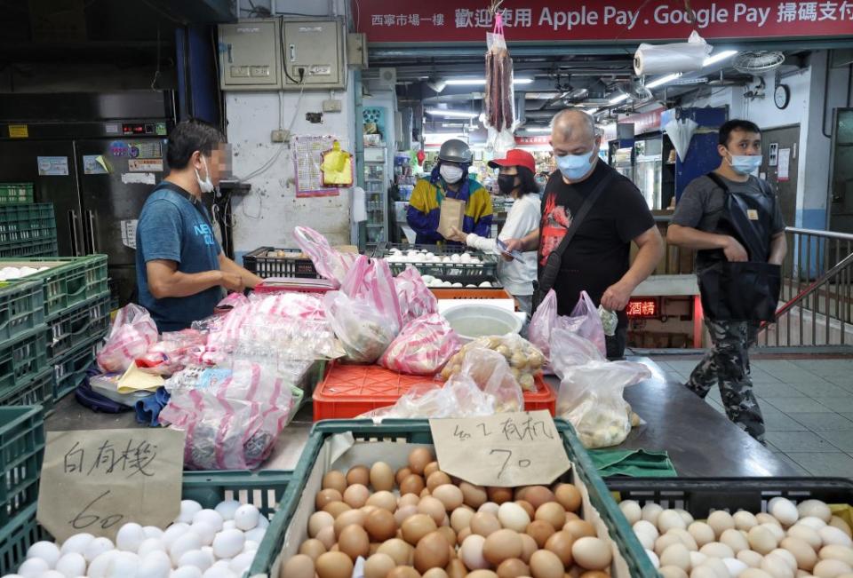 國內COVID-19疫情尚未趨緩，民眾7日上午前往台北市西寧市場採買食材，外出不忘配戴口罩。（中央社）