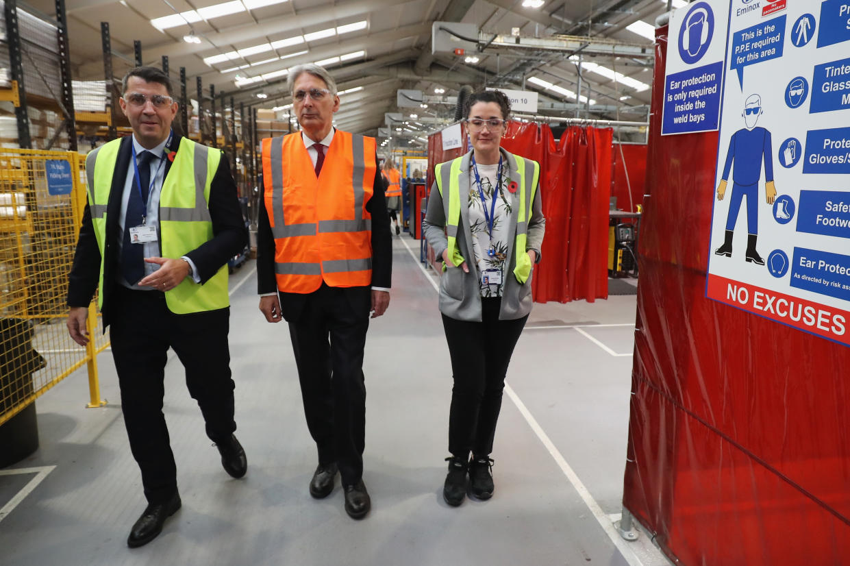 Britain’s Chancellor of the Exchequer Philip Hammond (C) talks with Eminox Managing Director Marc Runciman (L) and Eminox Supply Manager Rachel Eldridge (R) as he tours the Eminox factory. Photo: CHRISTOPHER FURLONG/AFP/Getty Images