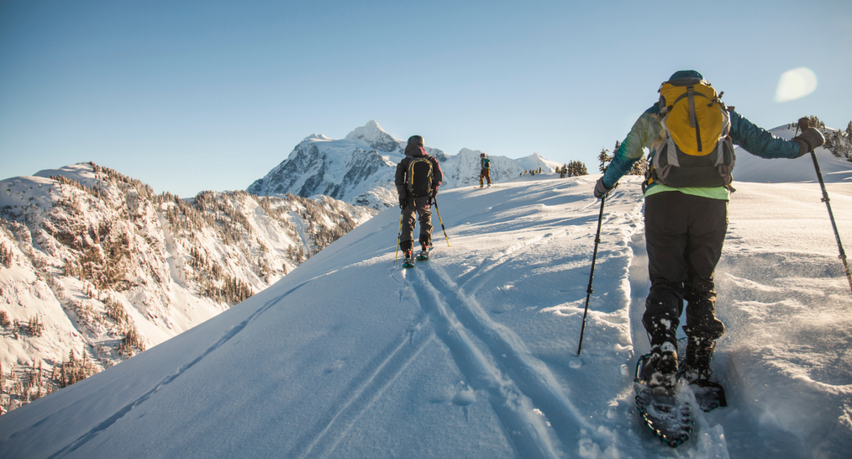 men on top of mountain snowshoeing in deep snow