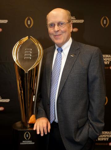 College Football Playoff Executive Director Bill Hancock poses with he College Football Playoff National Championship Trophy, Monday, July 14, 2014, in Irving, Texas. A rising gold football-shaped trophy will be the prize for the national champion in the new College Football Playoff. (AP Photo/Tony Gutierrez)