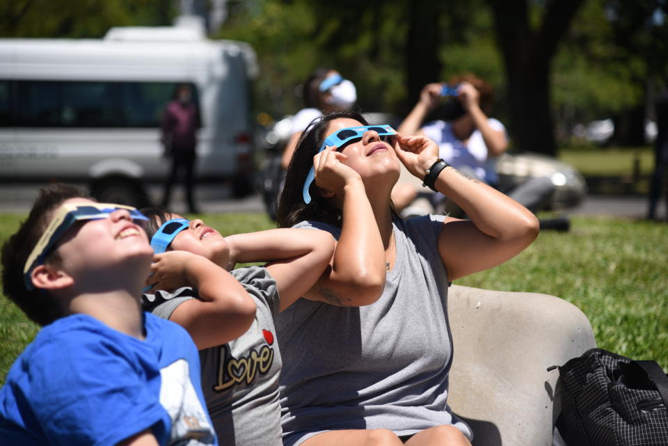 People watch solar eclipse using protective lenses in Buenos Aires, Argentina on Dec. 14, 2020. The total solar eclipse was visible in parts of Chile and Argentina. (Photo by Mariano Gabriel Sanchez/Anadolu Agency via Getty Images)