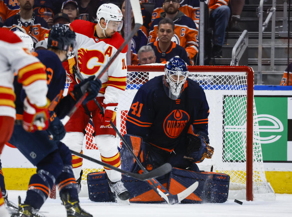 Calgary Flames forward Mikael Backlund, left, looks on as Edmonton Oilers goalie Mike Smith blocks the net during the second period of an NHL hockey Stanley Cup second-round playoff series game in Edmonton, Alberta, Sunday, May 22, 2022. (Jeff McIntosh/The Canadian Press via AP)