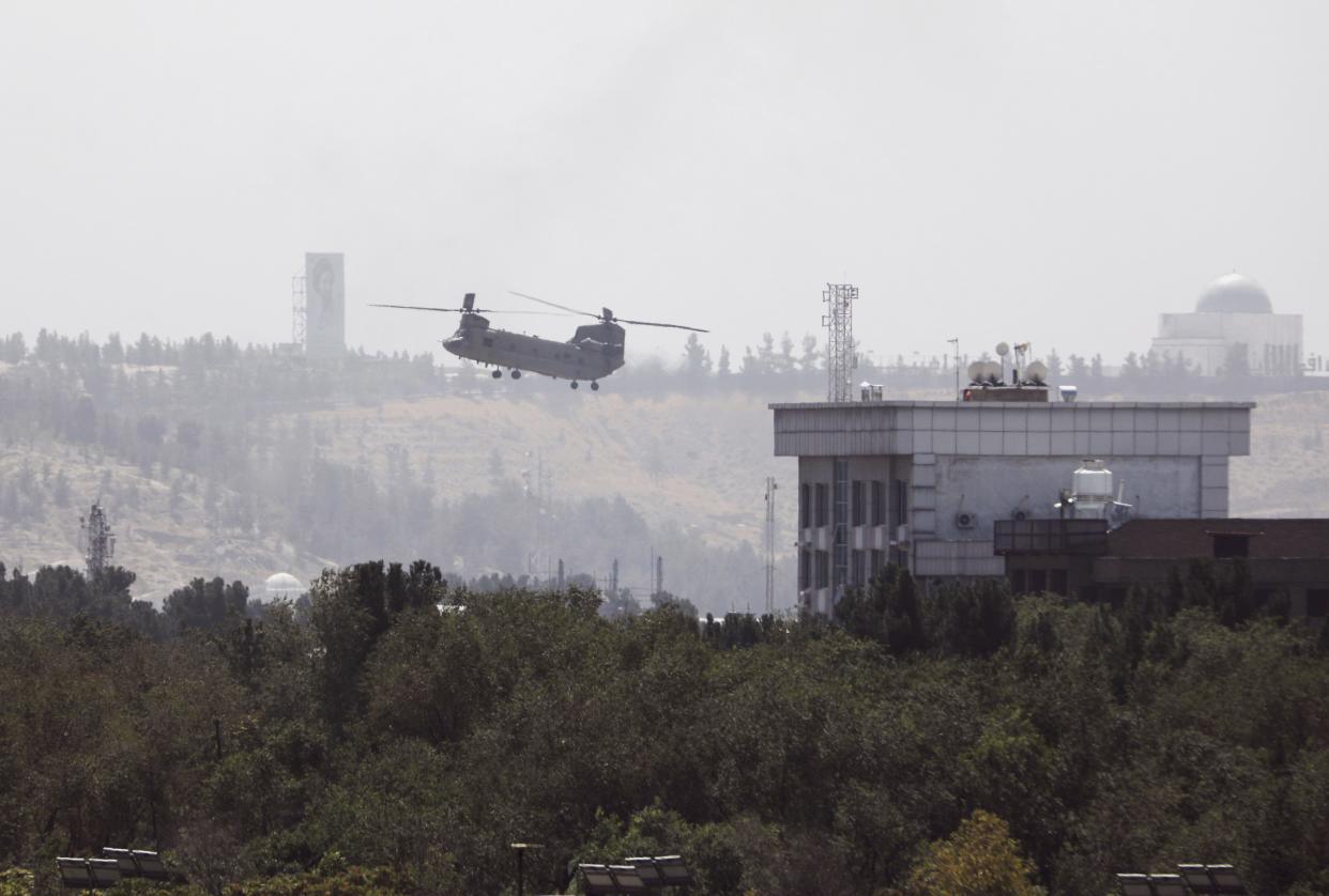 A U.S. Chinook helicopter flies near the U.S. Embassy in Kabul, Afghanistan on Sunday, Aug. 15, 2021. Helicopters are landing at the U.S. Embassy in Kabul as diplomatic vehicles leave the compound amid the Taliban advanced on the Afghan capital.