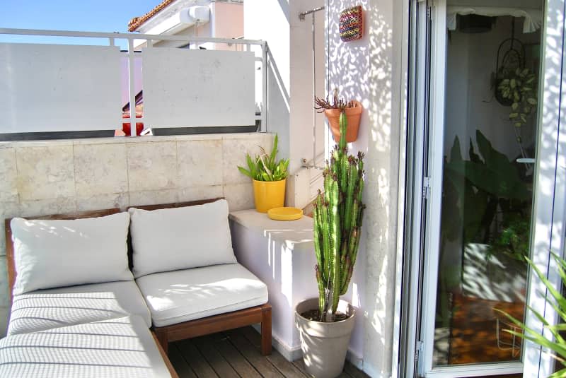 Potted plants and seating area of neutral toned balcony.