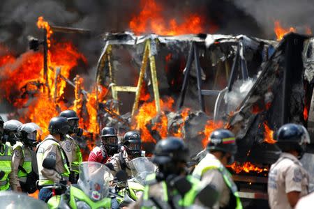 Riot security forces members congregate next to a government truck that was set on fire during a rally against Venezuelan President Nicolas Maduro's government in Caracas, Venezuela June 22, 2017. REUTERS/Christian Veron