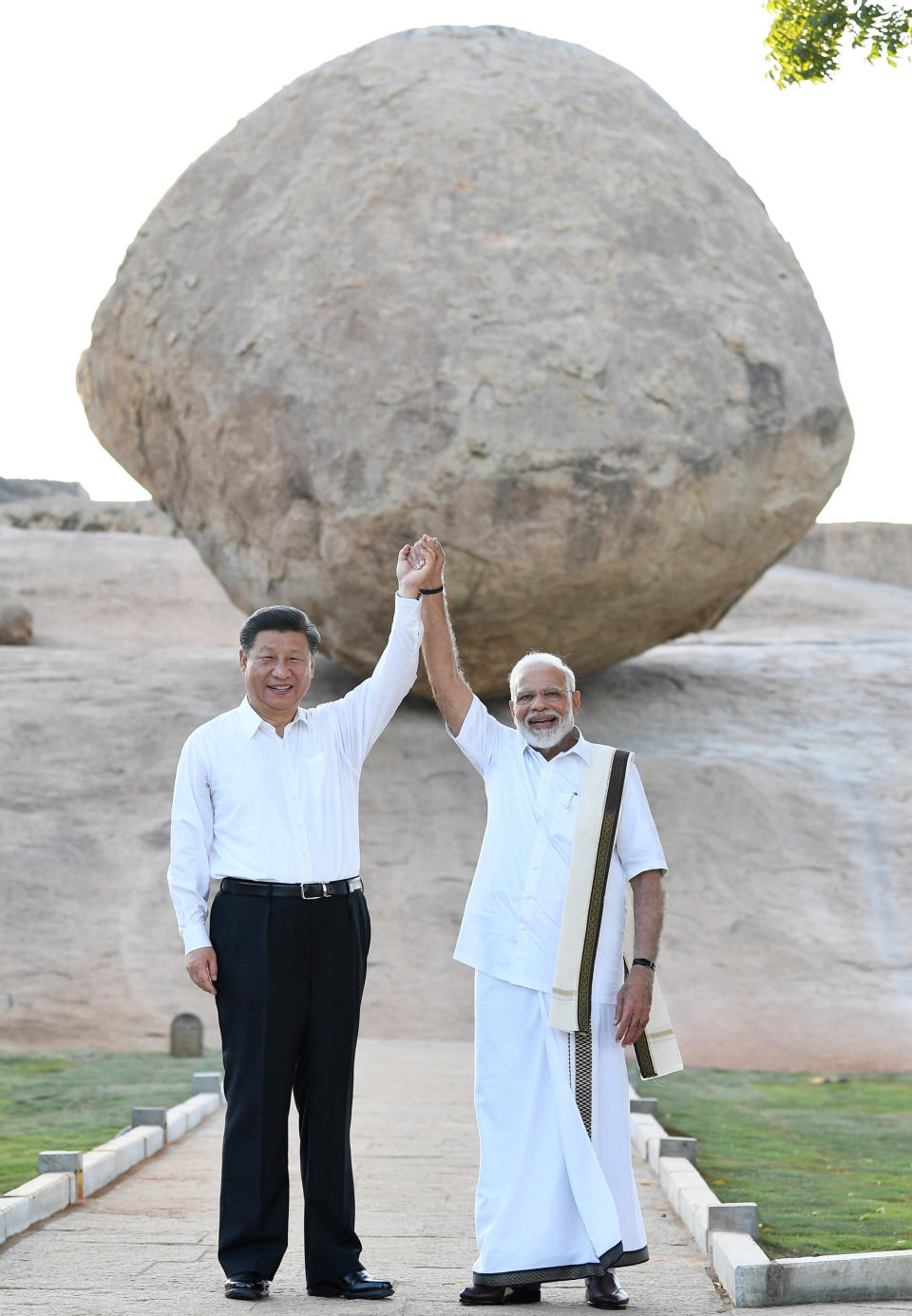 In this Friday, Oct. 11, 2019, handout photo provided by the Indian Prime Minister's Office, Chinese President Xi Jinping and Indian Prime Minister Narendra Modi raise hands together at Arjuna's Penance in Mamallapuram, India. Xi on Friday met with Modi at a time of tensions over Beijing's support for Pakistan in opposing India's downgrading of Kashmir's semi-autonomy and continuing restrictions on the disputed region. (Indian Prime Minister's Office via AP)