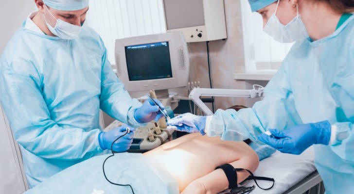 An image of two medical professionals performing a procedure on a patient