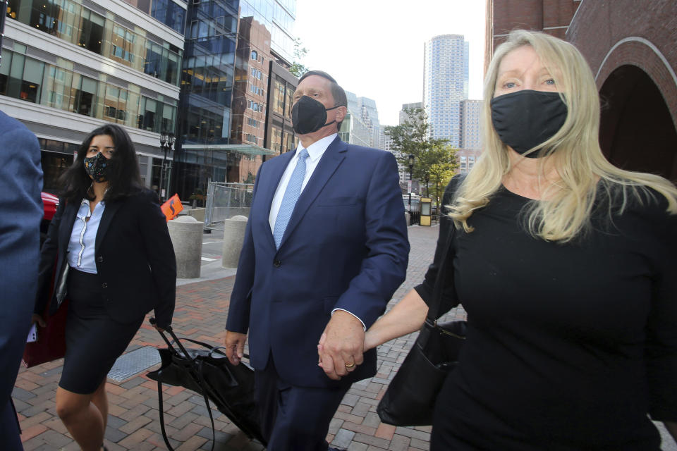 John Wilson, center, holds his wife's hand, right, as he leaves the John Joseph Moakley Federal Courthouse after the first day of his trial in the college admissions scandal, Monday, Sept.13, 2021, in Boston. (AP Photo/Stew Milne)