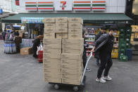 A worker carries boxes containing face masks to a pharmacy at a shopping district in Seoul, South Korea, Tuesday, Jan. 28, 2020. Panic and pollution drive the market for protective face masks, so business is booming in Asia, where fear of the coronavirus from China is straining supplies and helping make mask-wearing the new normal. (AP Photo/Ahn Young-joon)
